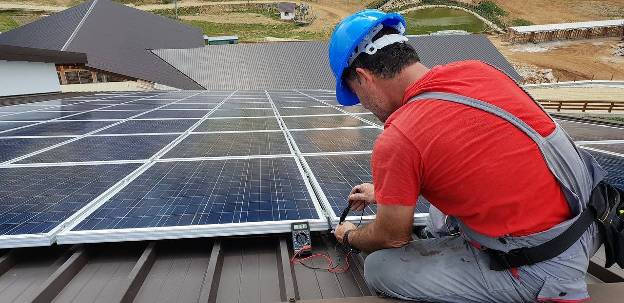 worker wiring solar panels to house